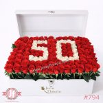Cofre blanco con 130 rosas rojas frescas y números blancos personalizados para regalo floral en ocasiones especiales.