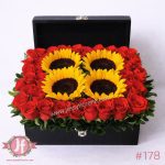 Cofre de madera con 35 rosas y 4 girasoles frescos, arreglo floral elegante para regalar en ocasiones especiales.